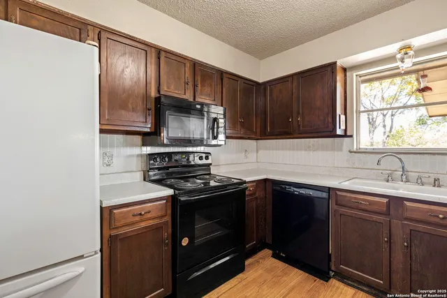 a kitchen with stainless steel appliances granite countertop wooden cabinets a dining table and chairs