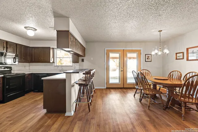 a view of a dining room with furniture a kitchen and chandelier