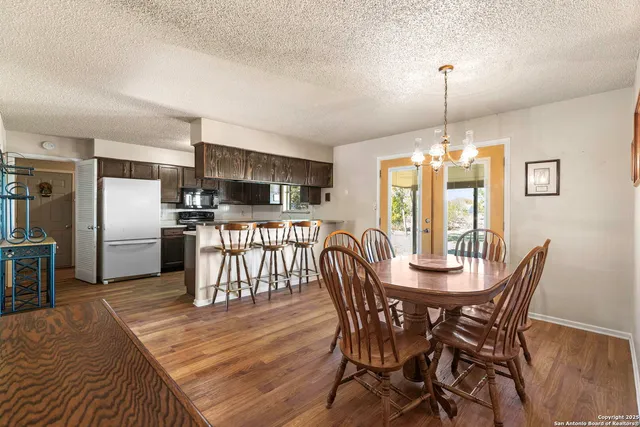 a kitchen with stainless steel appliances a refrigerator a stove top oven and a dining table with wooden floor