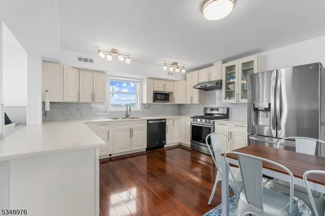 a kitchen with a refrigerator a stove a sink dishwasher with a dining table and chairs