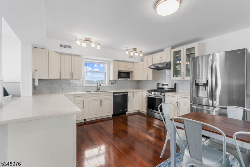 129 Franklin Avenue, Unit B Seaside Heights, NJ 08751 - Photo 4 of 22 a kitchen with a refrigerator a stove a sink dishwasher with a dining table and chairs