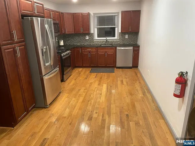 a large kitchen with stainless steel appliances granite countertop a refrigerator and a sink