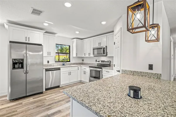 a kitchen with stainless steel appliances granite countertop a refrigerator sink and stove