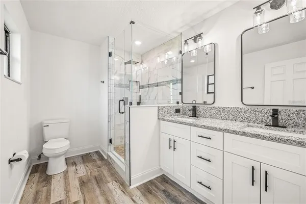 a bathroom with a granite countertop sink a toilet and a shower