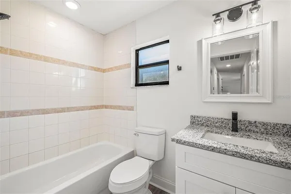 a bathroom with a granite countertop sink a toilet and bathtub
