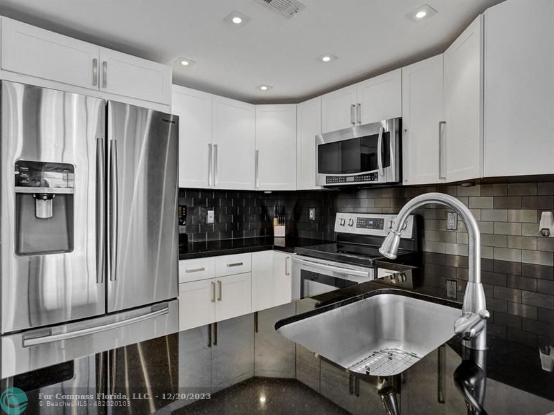a kitchen with stainless steel appliances a microwave a sink and cabinets