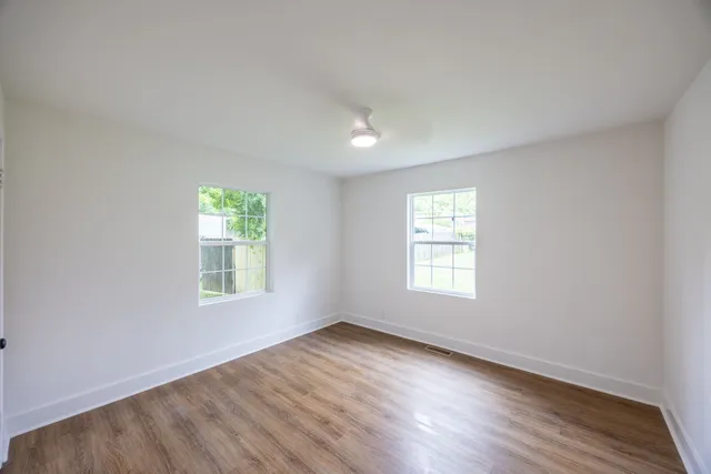 an empty room with wooden floor and windows