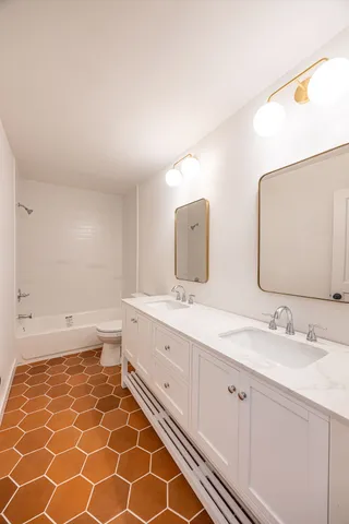 a bathroom with a double vanity sink mirror and toilet