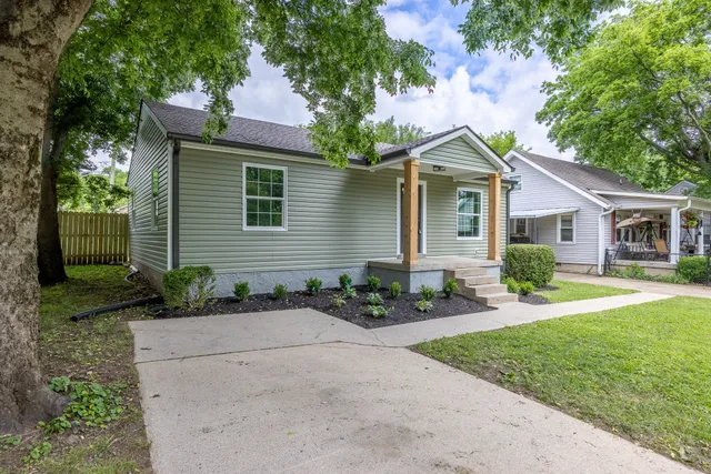 a front view of a house with a yard and potted plants