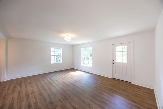 an empty room with wooden floor and windows