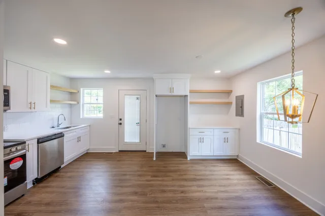 a large kitchen with cabinets wooden floor and a window