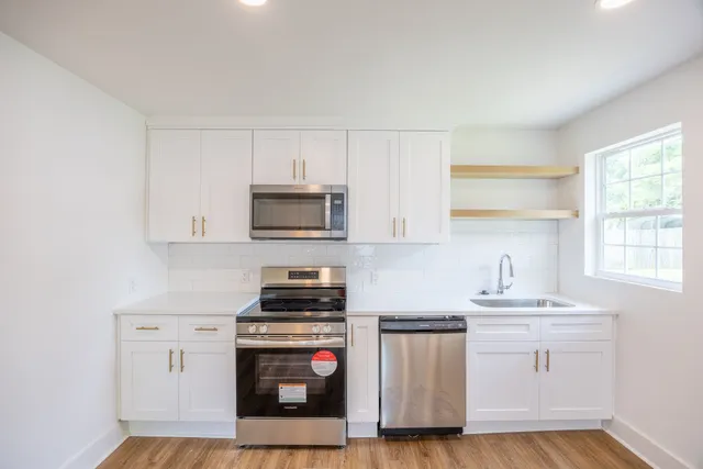 a kitchen with white cabinets and appliances