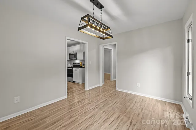 a view of an empty room with window and wooden floor
