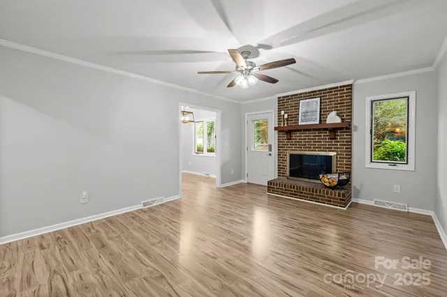 an empty room with windows a fireplace and wooden floor