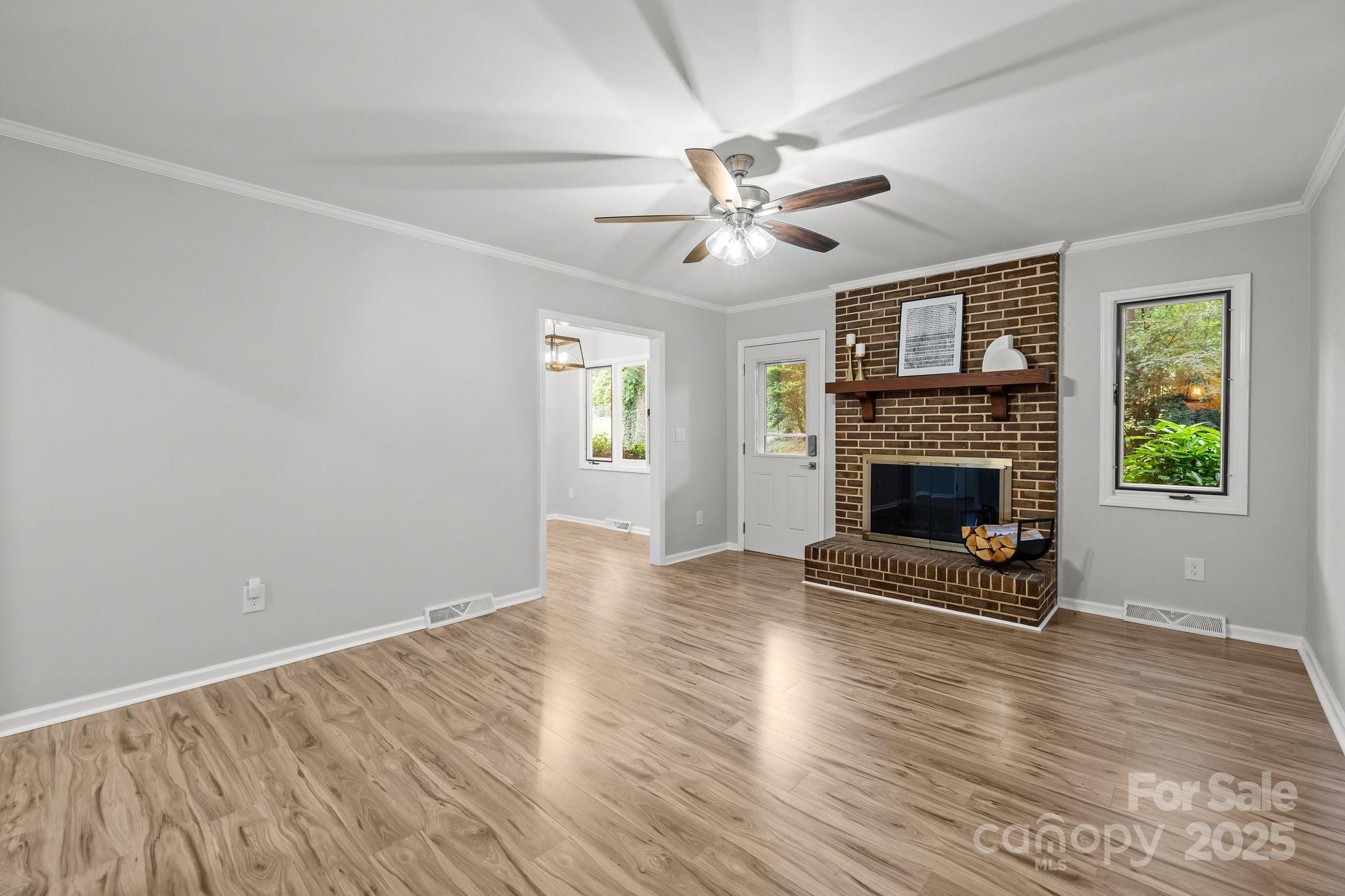 13446 Idlefield Lane Matthews, NC 28105 - Photo 13 of 42 an empty room with windows a fireplace and wooden floor