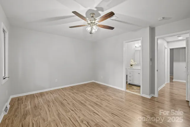 an empty room with wooden floor and ceiling fan