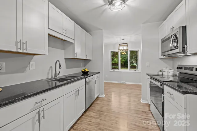 a kitchen with stainless steel appliances granite countertop a sink stove and cabinets