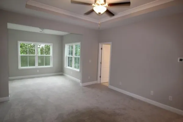 an empty room with a chandelier fan and windows