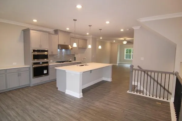 a large white kitchen with a stove a sink and dishwasher with wooden floor