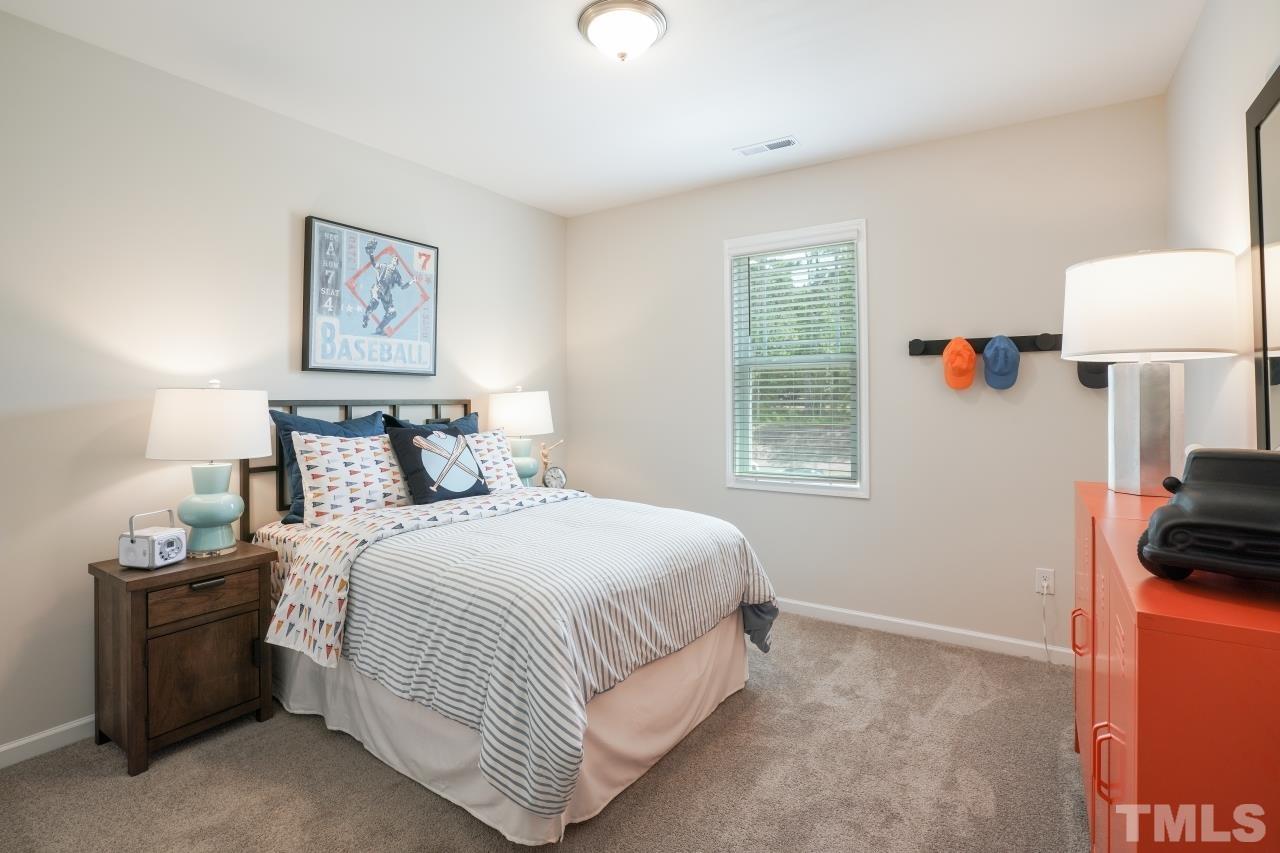 232 Brody Pine Way Garner, NC 27529 - Photo 26 of 35 a bedroom with a bed and a lamp on dresser