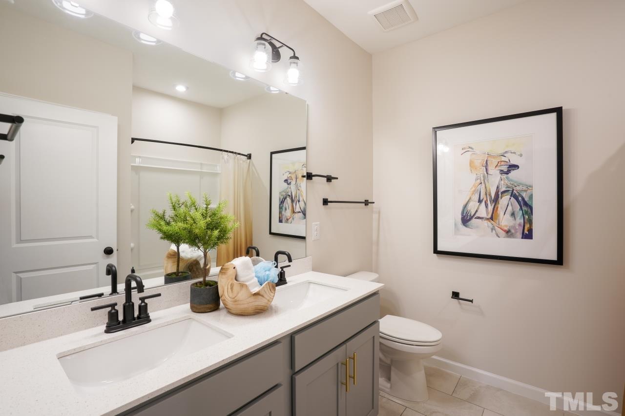 232 Brody Pine Way Garner, NC 27529 - Photo 32 of 35 a bathroom with a sink a toilet and a large mirror