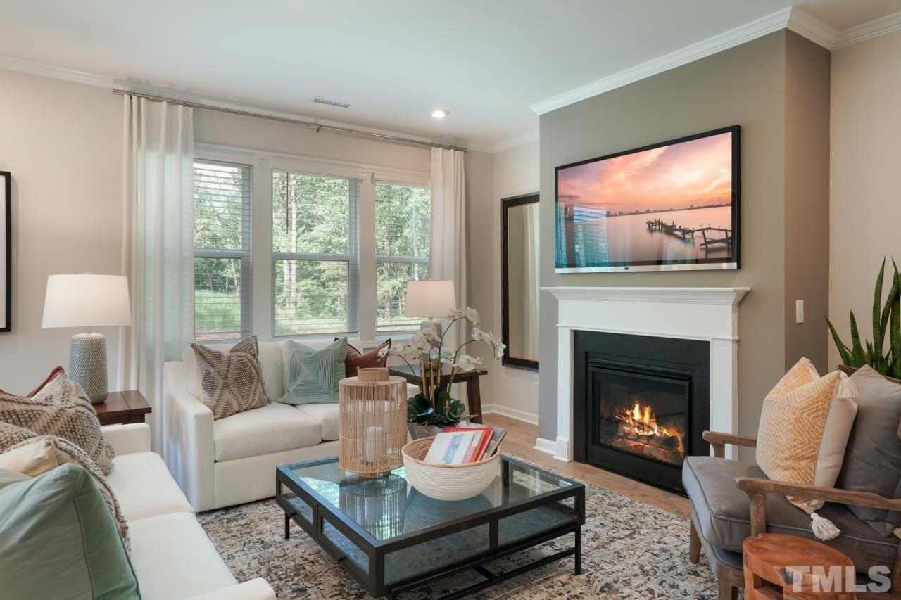232 Brody Pine Way Garner, NC 27529 - Photo 9 of 35 a living room with furniture a fireplace and a flat screen tv