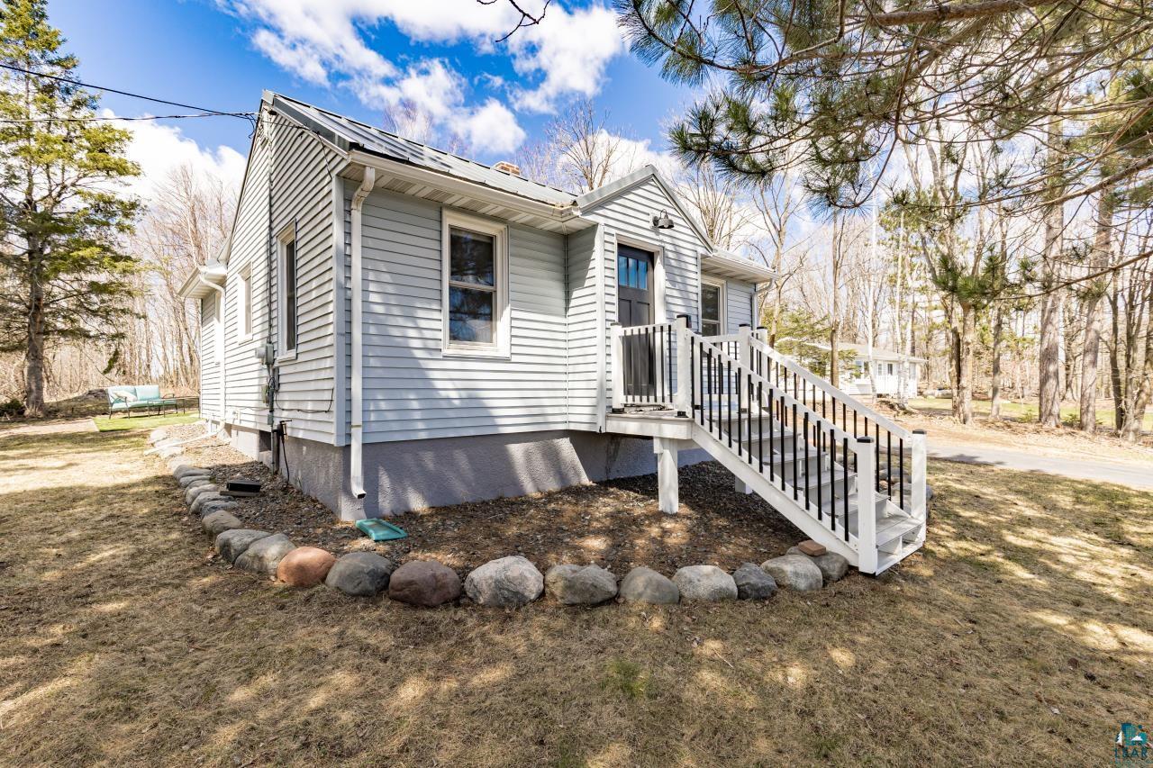 3645 Haines Road Hermantown, MN 55811 - Photo 12 of 35 Light blue siding exterior featuring a dark front door, white trim, and a white deck with dark balusters