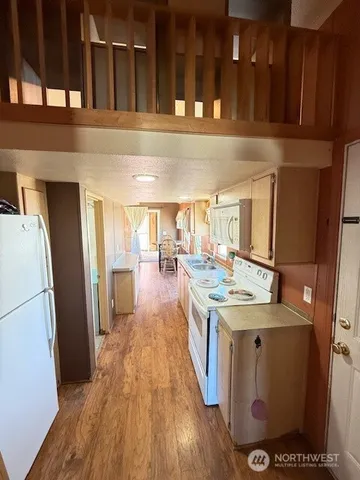a view of a kitchen with refrigerator and wooden floor