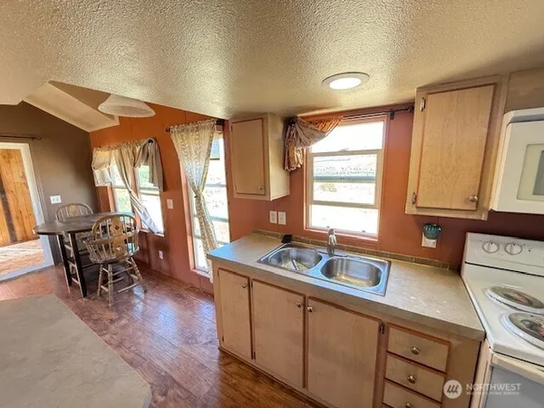 a kitchen with kitchen island a sink a stove wooden floor and a refrigerator