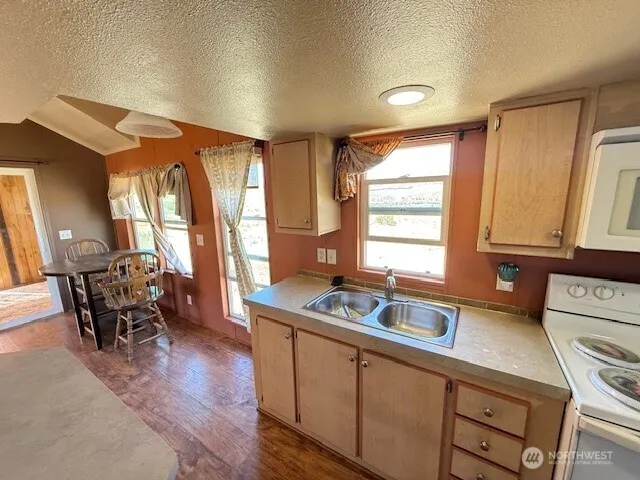 a kitchen with kitchen island a sink a stove wooden floor and a refrigerator
