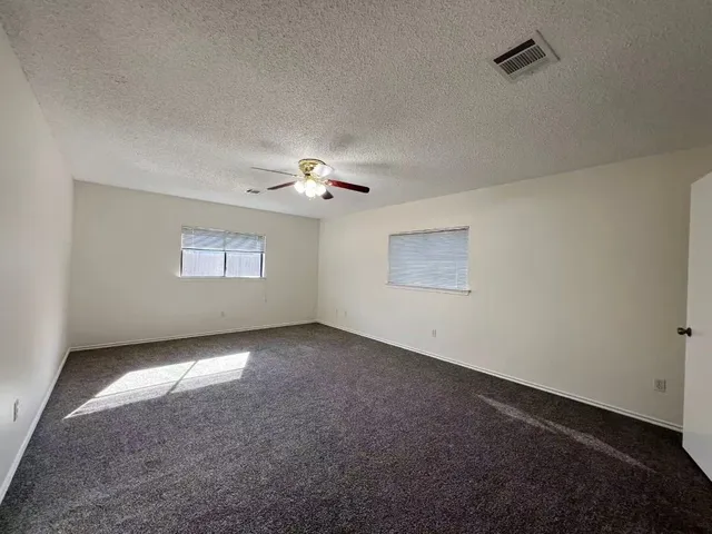 an empty room with windows and chandelier fan