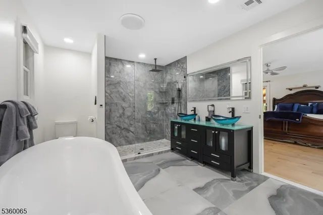a bathroom with a tub sink mirror vanity and toilet