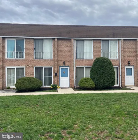 a view of a brick house with a big yard and large trees