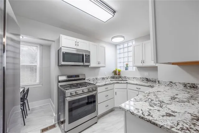 a kitchen with granite countertop a sink stove and microwave
