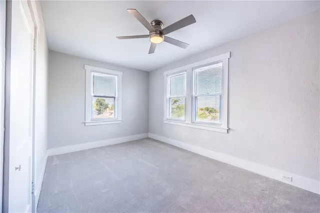 an empty room with ceiling fan and windows
