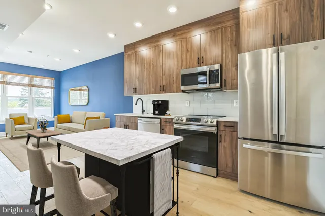 a kitchen with a refrigerator a stove a microwave and island with wooden floor