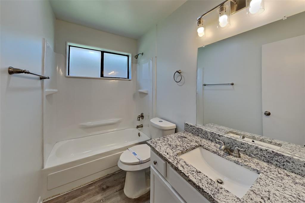 7809 Meadowlark Lane Rowlett, TX 75088 - Photo 15 of 18 a bathroom with a granite countertop sink a toilet and shower