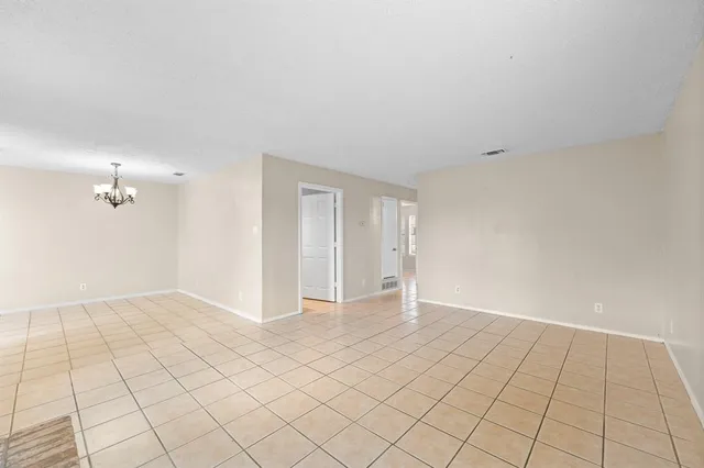 a view of an empty room and chandelier fan
