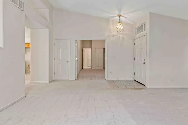 an empty room with chandelier fan and closet area