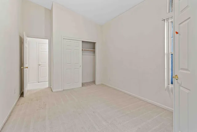 an empty room with chandelier fan and windows