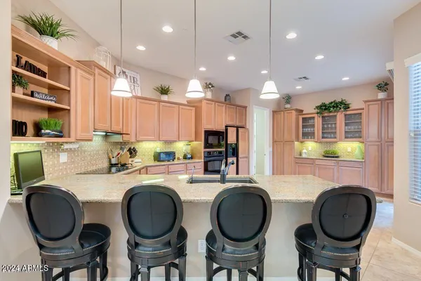 a kitchen with stainless steel appliances granite countertop a table chairs and a refrigerator