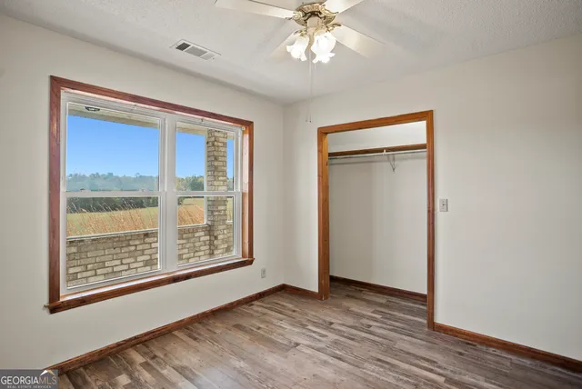 a view of an empty room with a window and wooden floor