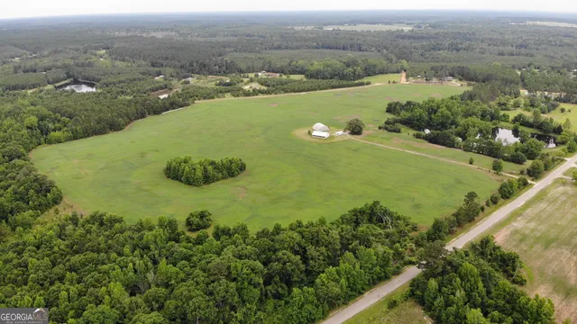 an aerial view of a residential houses with outdoor space and trees all around