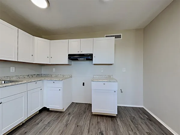 a kitchen with wooden floors and white cabinets