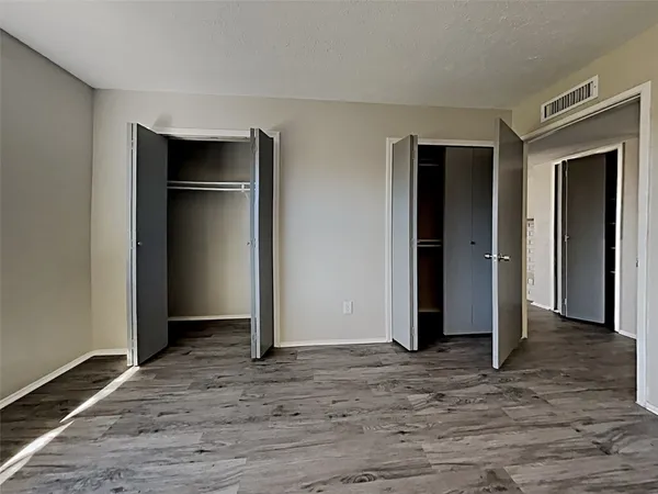 an empty room with wooden floor closet and entryway