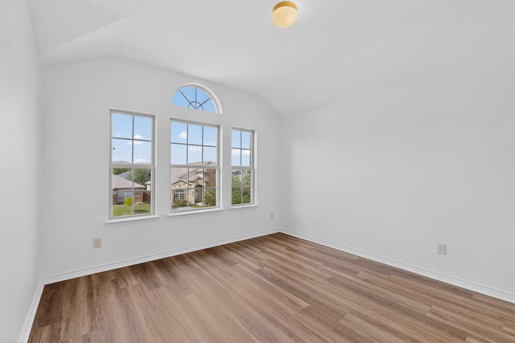 426 Harding Lane Lavon, TX 75166 - Photo 34 of 40 Vaulted ceiling room featuring three large windows with an arched transom, wood-finish flooring, and white baseboards
