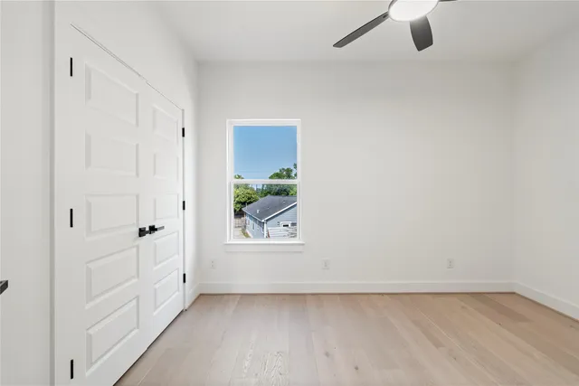 an empty room with a window and a ceiling fan