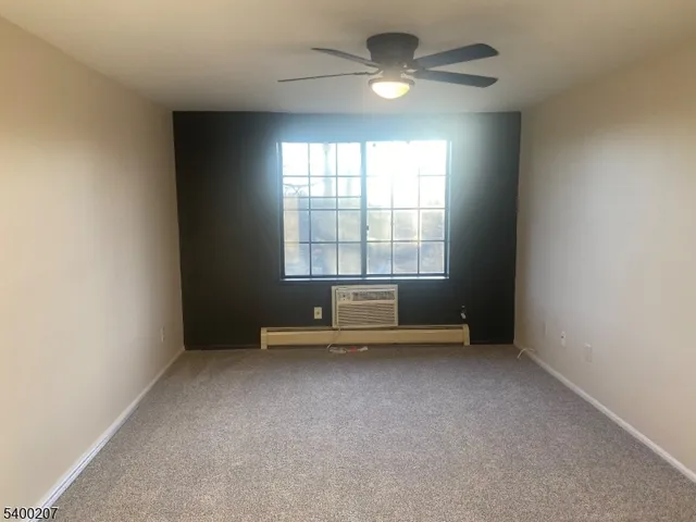an empty room with chandelier fan and windows