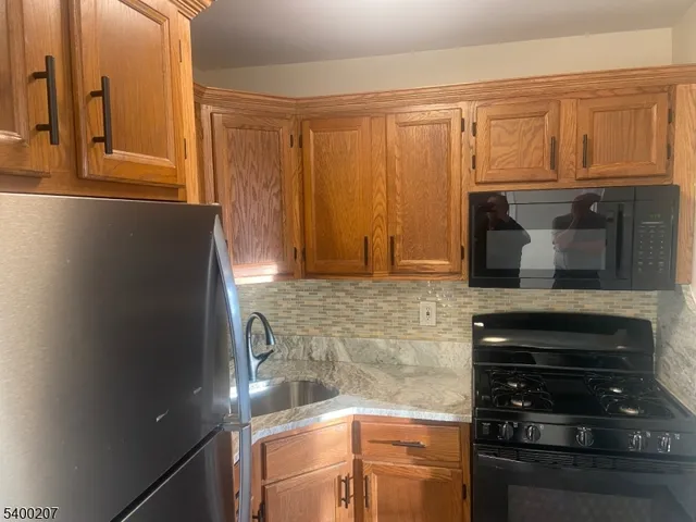 a kitchen with granite countertop a refrigerator and cabinets
