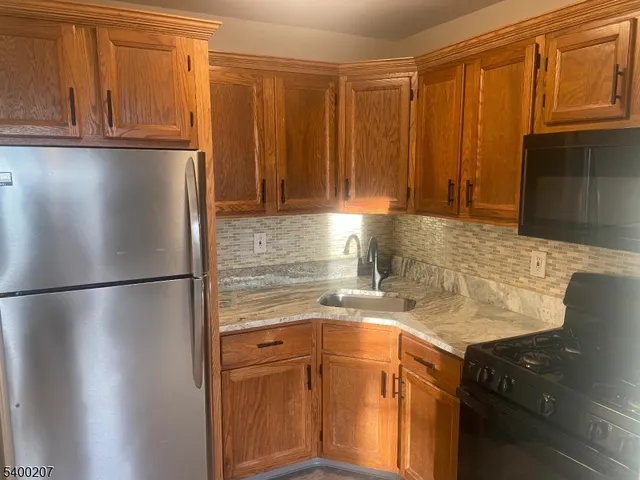 a kitchen with stainless steel appliances granite countertop a refrigerator a stove and a sink